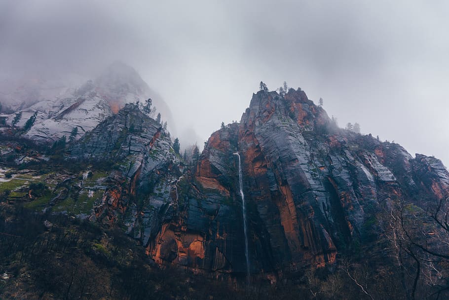 brown cliff during foggy season, lava erupted mountain under cloudy sky during daytime HD wallpaper