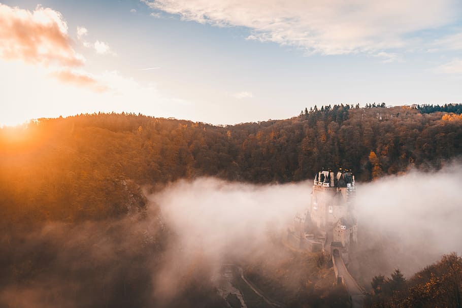 green trees under blue sky and white clouds at daytime, white and black castle surround with fogs and trees under blue sky during daytime HD wallpaper