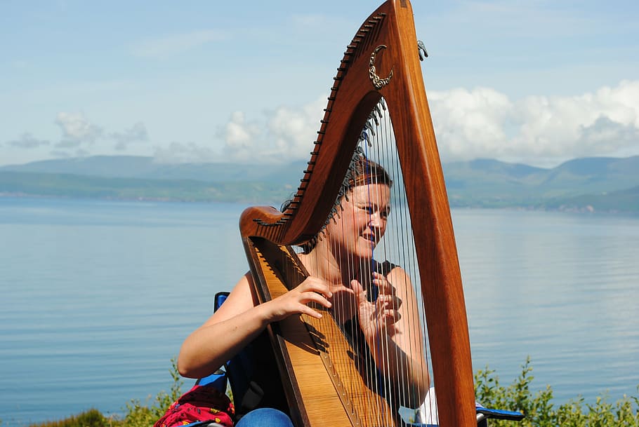 woman playing harp near bodies of water during daytime, music