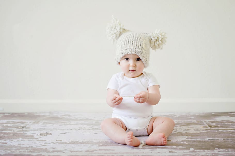 baby wearing white onesie with beige bubble cap sitting on the floor, HD wallpaper