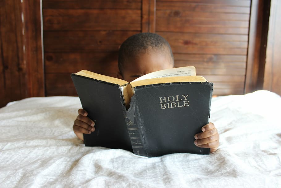 boy lying on bed reading Holy Bible, child, african, education, HD wallpaper