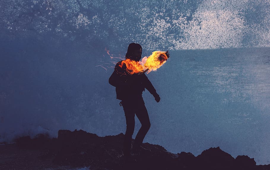 silhouette of person near flame on mountain during nighttime HD wallpaper
