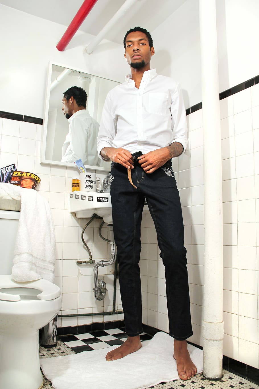 man wearing white dress shirt and black pants standing in comfort room beside mirror holding belt buckle, barefoot man wearing black pants and white dress shirt standing on towel inside bathroom, HD wallpaper