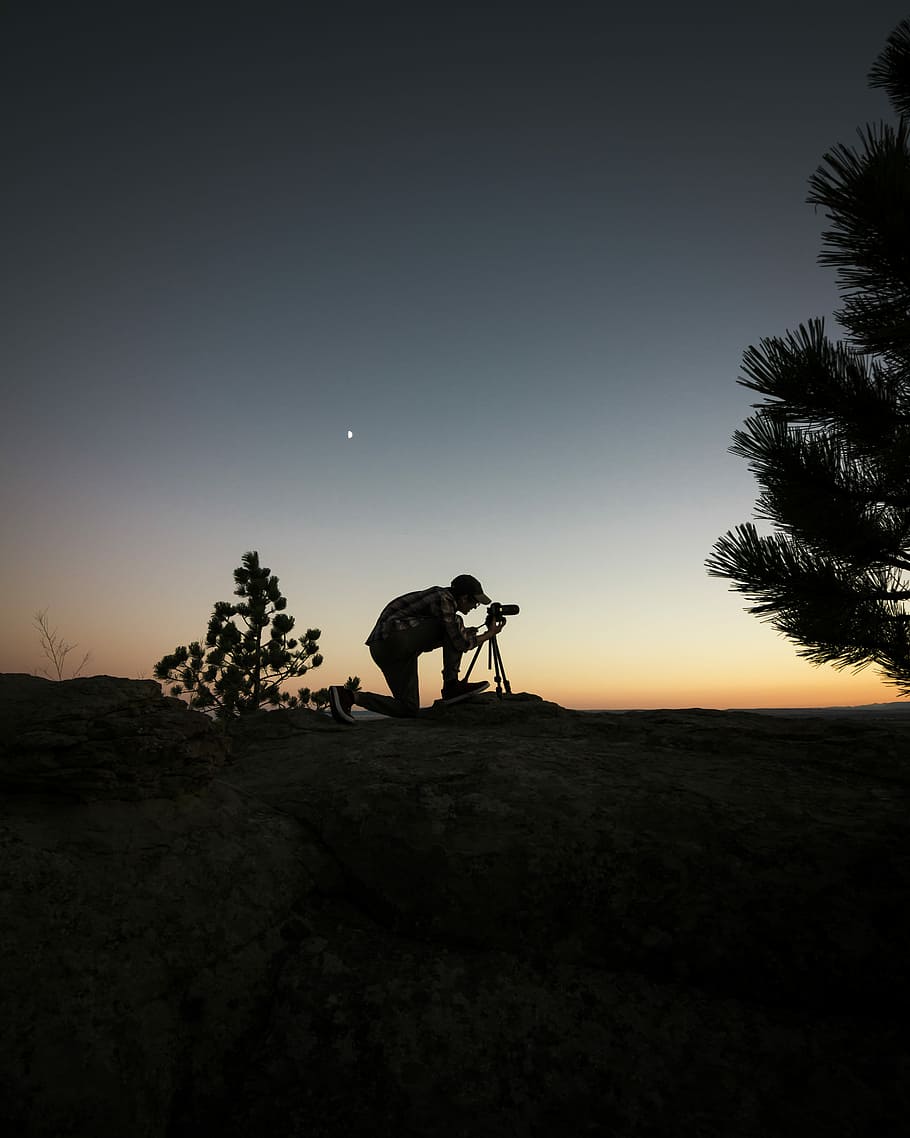 silhouette photography of man capturing photo during night time, man holding camera beside tree HD wallpaper