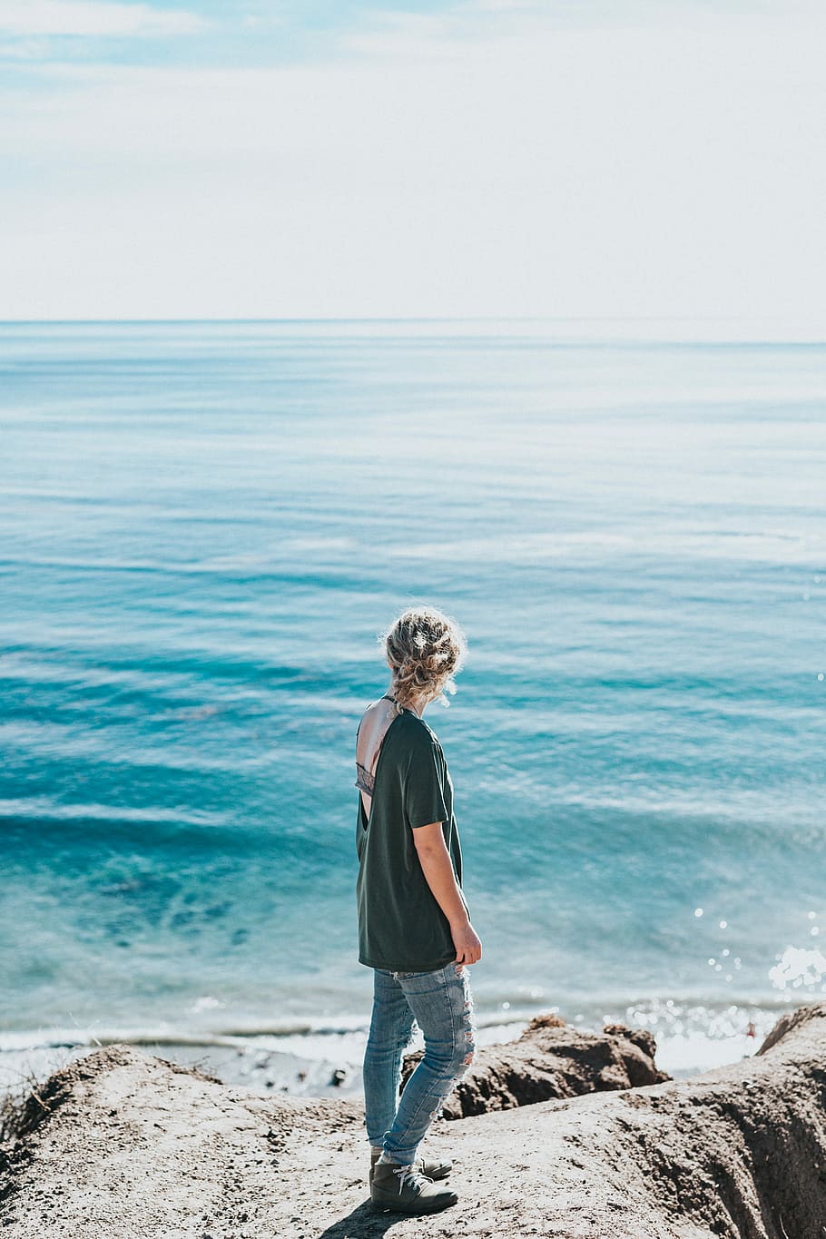 woman standing next to sea, woman in black shirt standing near body of water looking at sea during daytime HD wallpaper