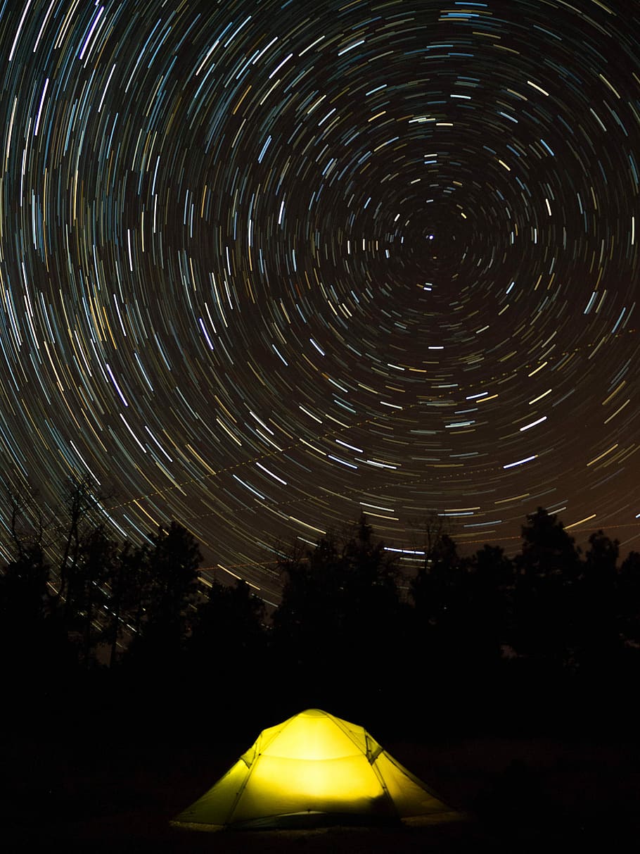 star trail photography of yellow camping tent, long exposure stars photography of yellow tent behind trees HD wallpaper