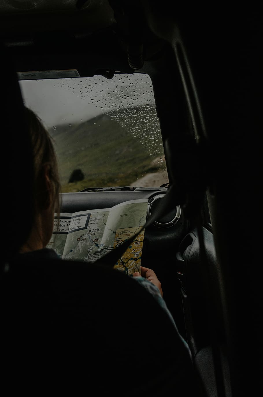 person sitting on front passenger seat holding map, person holding map inside car