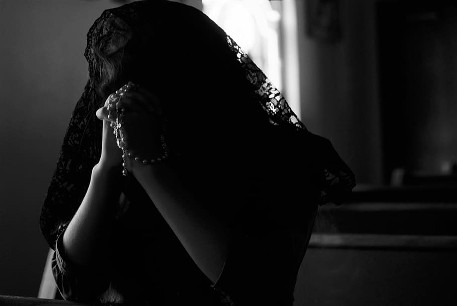 grayscale photography of woman praying while holding prayer beads, woman praying while holding rosary