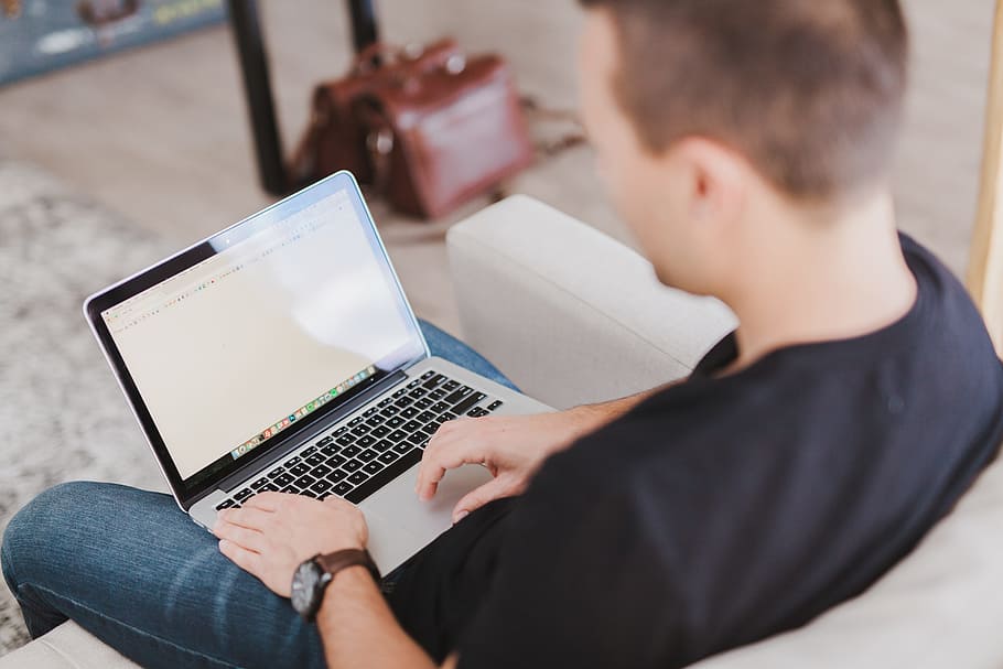 person sitting on gray sofa with MacBook Pro, typing, work HD wallpaper
