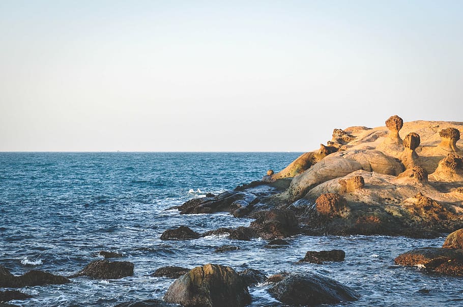 brown rocks on sea overlooking horizon at daytime, boulders, near