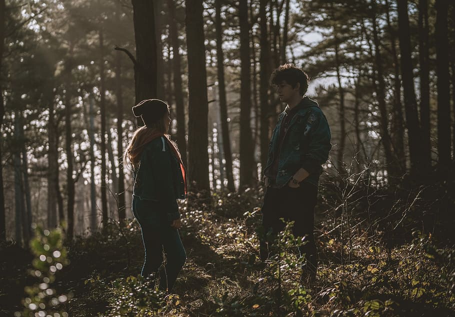 couple in woods during daytime, man and woman in the middle of the forest.