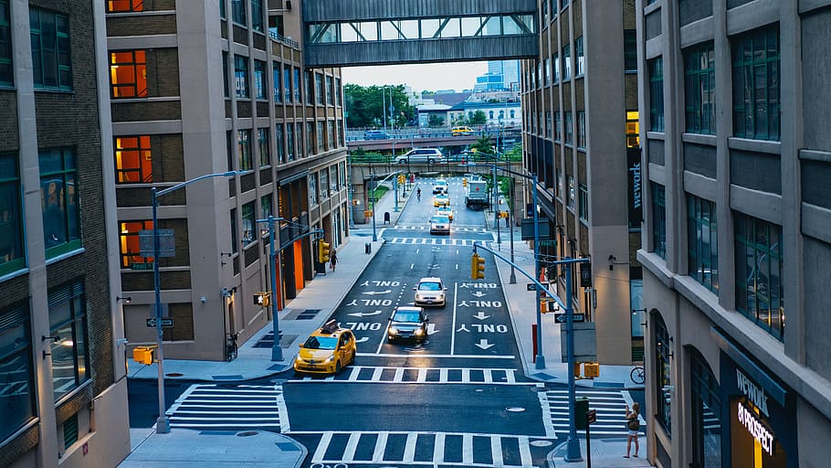 road between brown and black high-rise buildings, yellow taxi parked near highrise building at daytime HD wallpaper