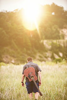 man with cut-away guitar on back walking away photo, outdoors HD wallpaper
