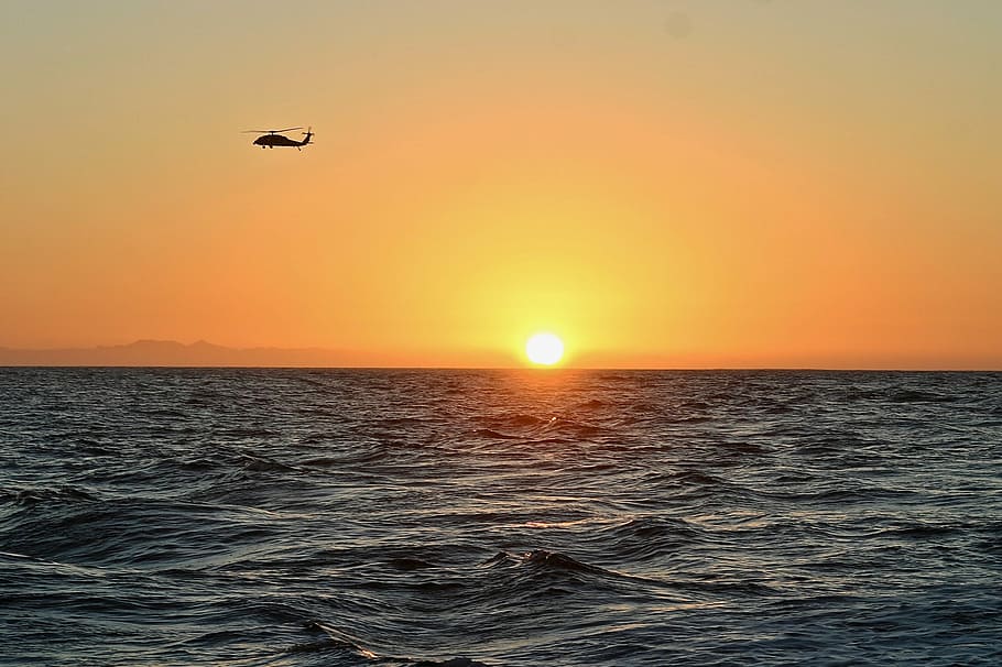 silhouette of helicopter flying above body of water, helicopter flying over sea HD wallpaper
