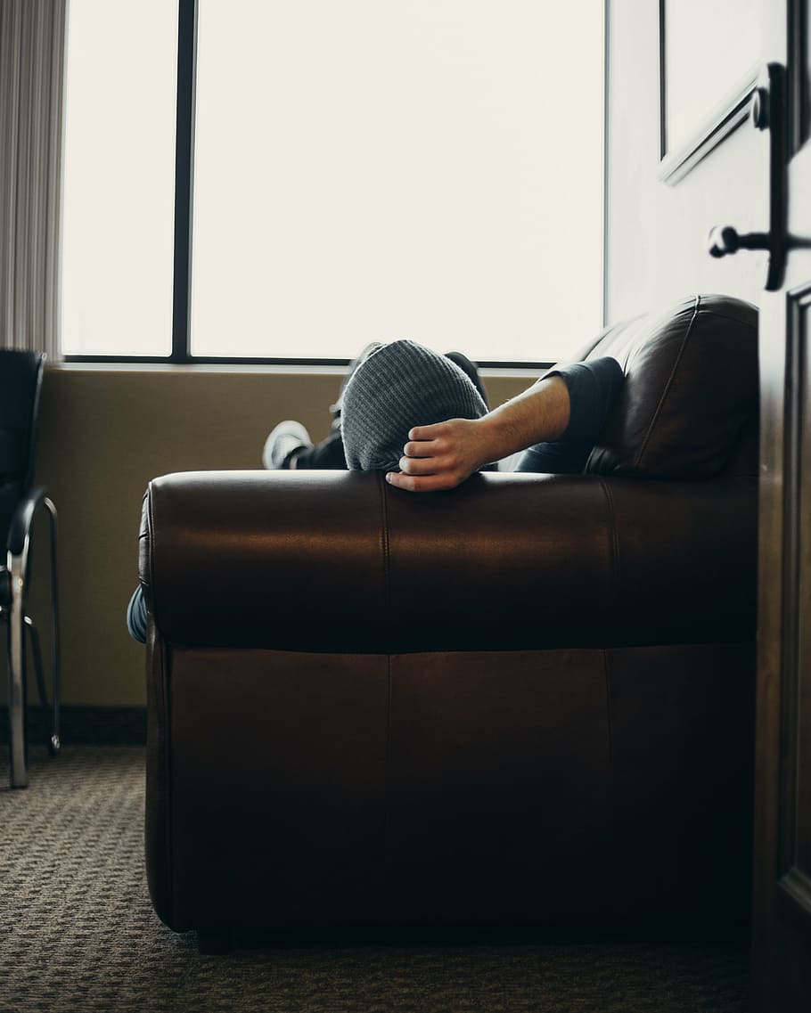 person lying on brown leather sofa in front of window, indoor HD wallpaper