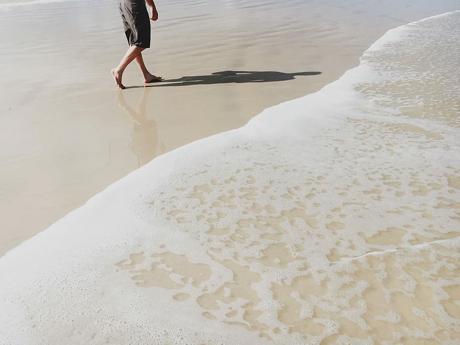 man in gray shorts walking on beach, person walking near seashore HD wallpaper