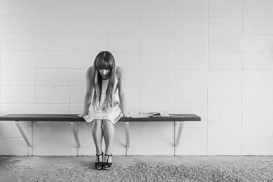 grayscale photography of woman sitting on bench, worried girl