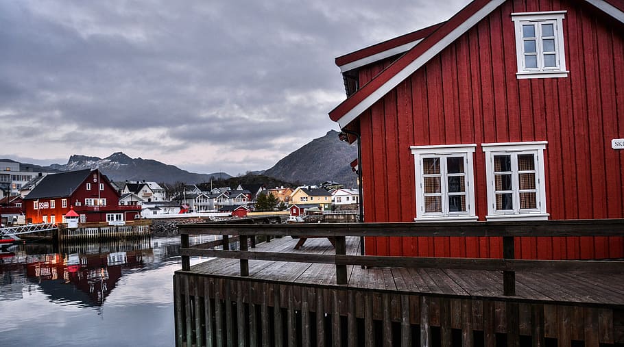 red and white house beside grey calm body of water at daytime HD wallpaper