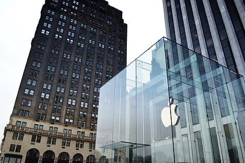 glass Apple company building beside high rise building under white sky HD wallpaper