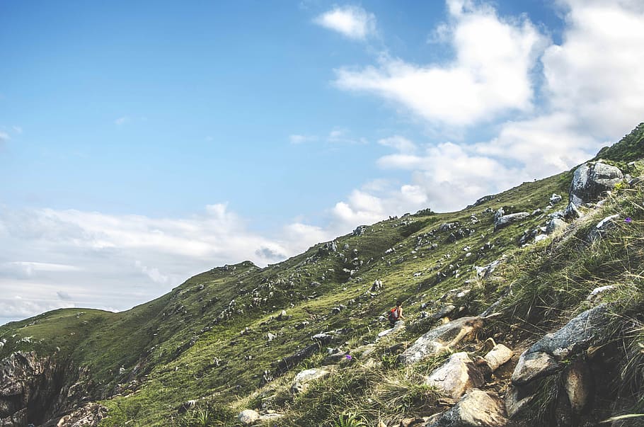 person walking on mountain during daytime, person climbing hill under cloudy sky HD wallpaper