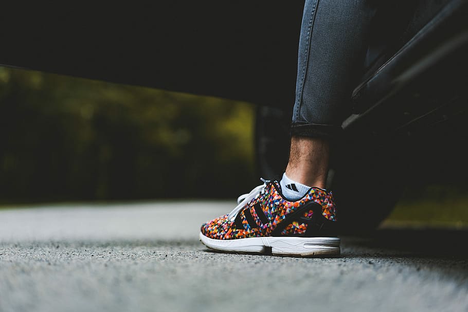 Prism, person wearing unpaired black and multicolored adidas running shoe