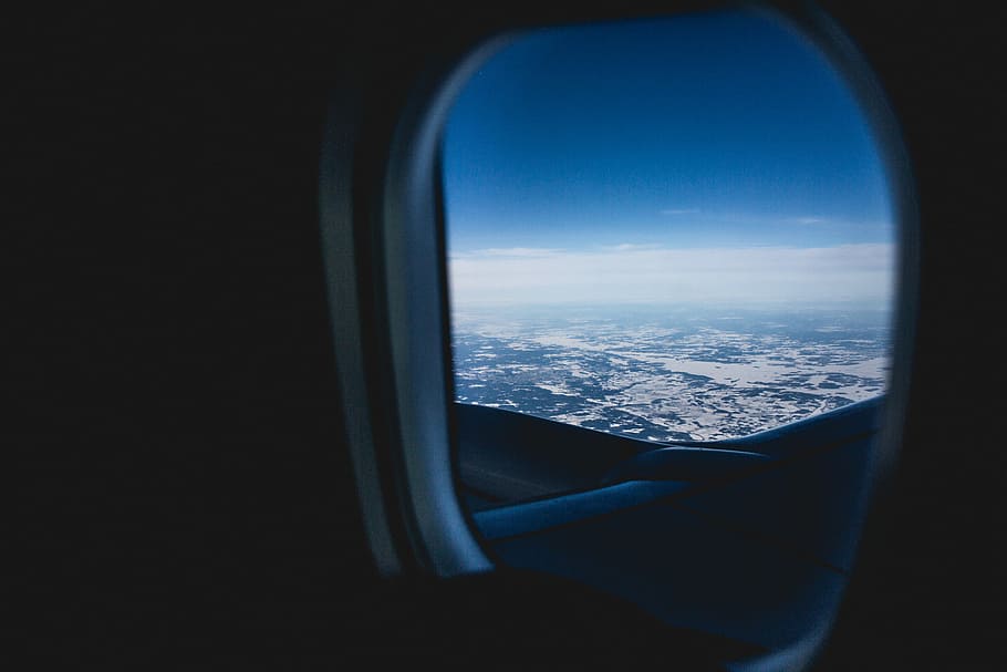 selective focus photography of airplane window, person taking photo inside airplane