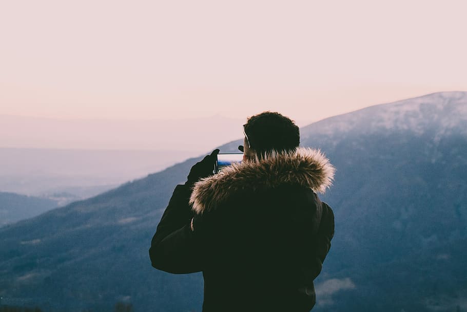man taking photo on hills, man wearing parka hoodie taking photo of mountain range HD wallpaper