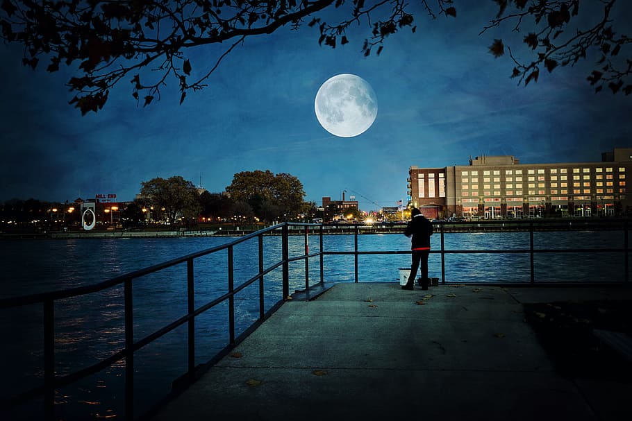 person standing near the railing while staring at the moon, super moon