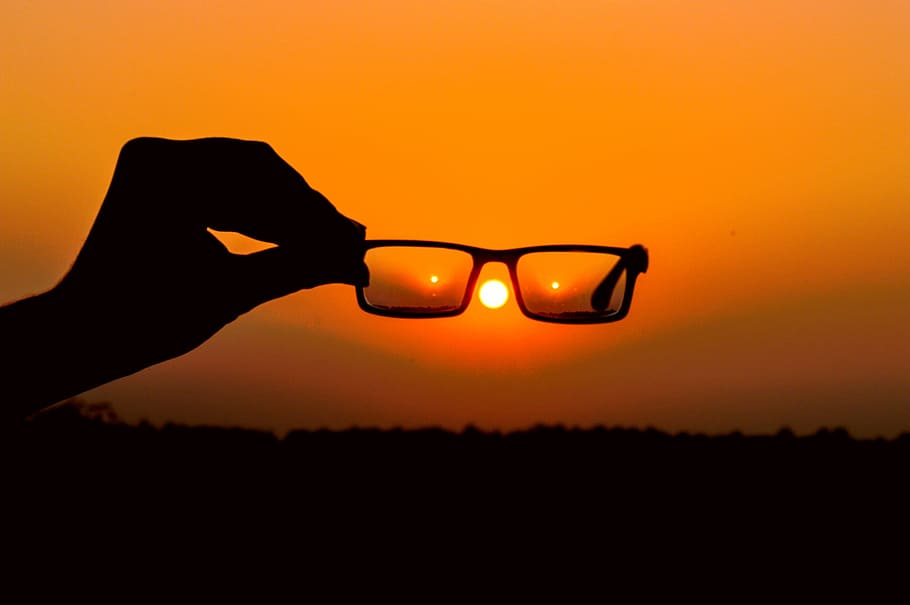 Silhouette of Person's Hand Holding Eyeglasses during Golden Hour HD wallpaper
