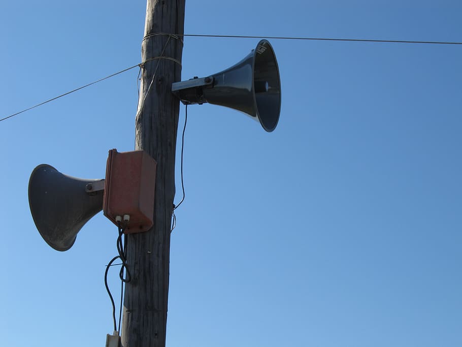 two gray megaphones on brown electric post, loudspeakers, sound