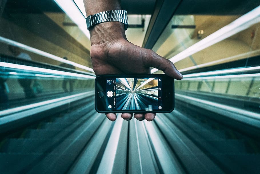 person holding iPhone while taking an empty walkalator, escalators HD wallpaper