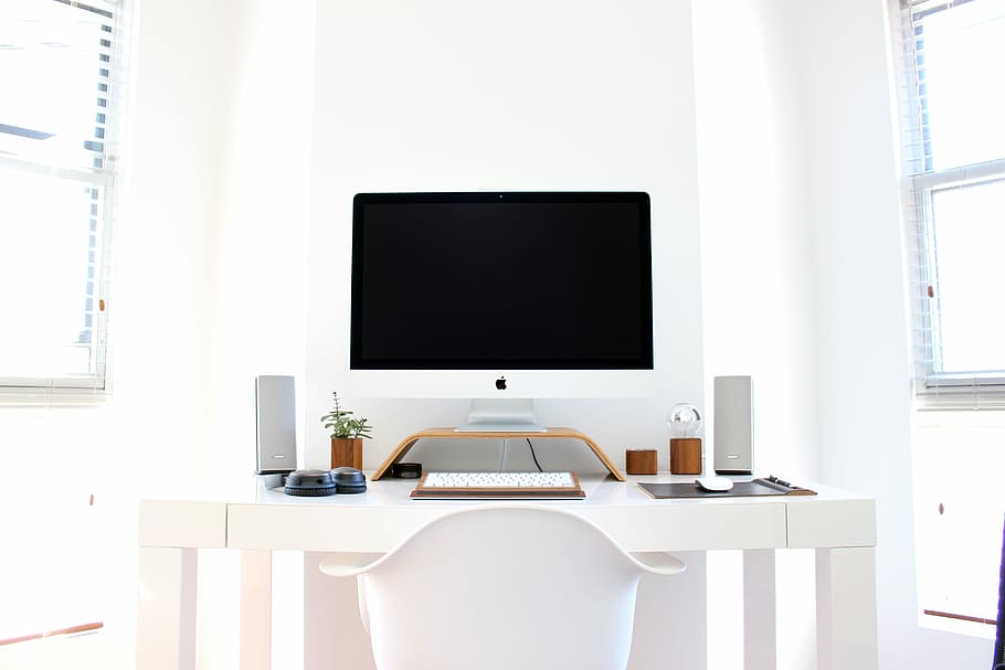 iMac on top of table, silver iMac beside Apple Keyboard on white wooden table