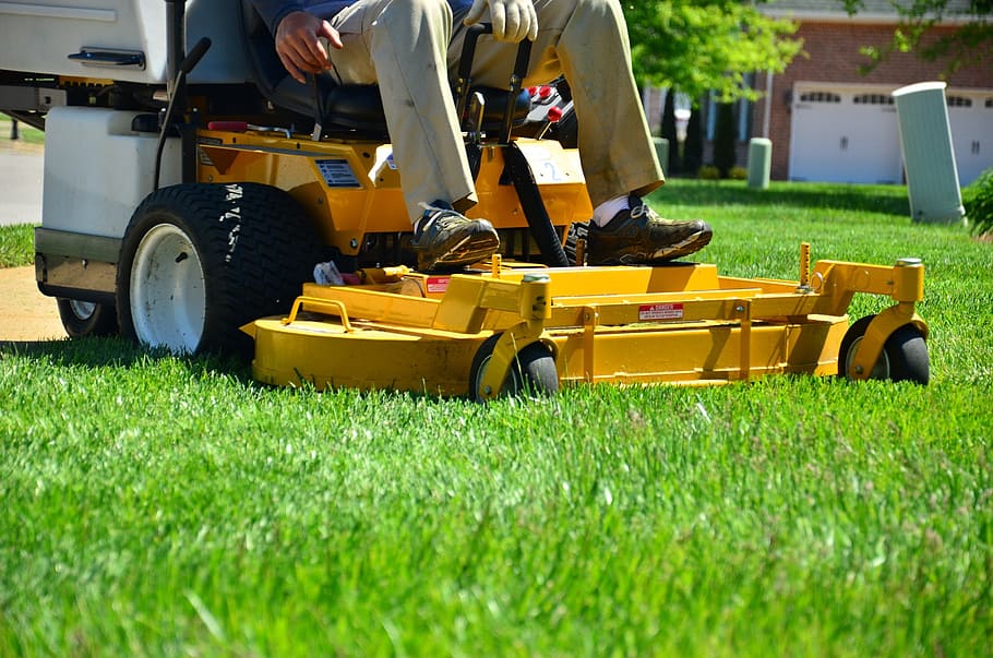 person sitting on yellow zero-turn lawn mower, lawn care, lawn maintenance