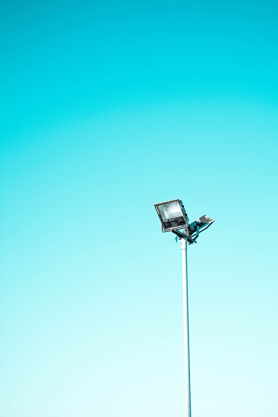 white and black light post under blue sky, gray and black flood light