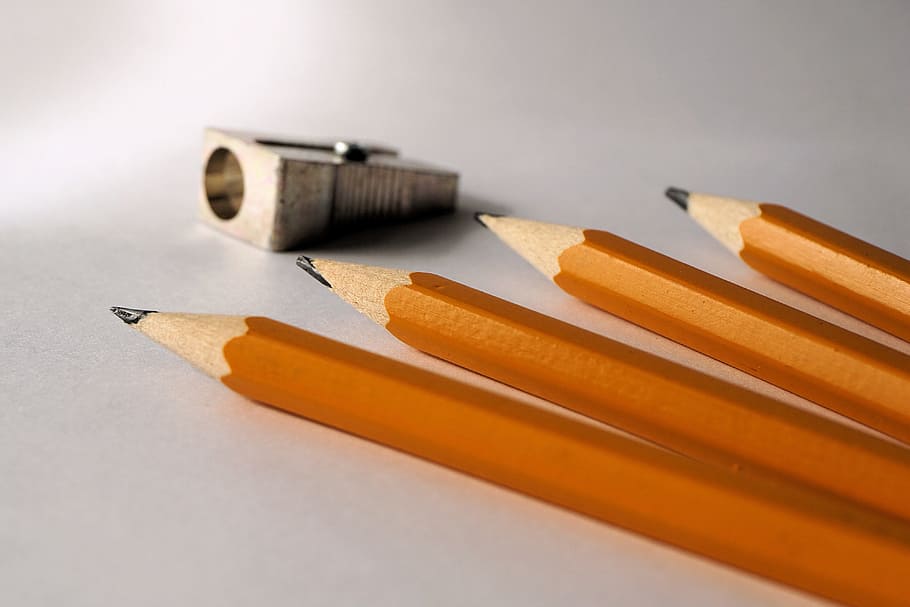 four brown pencils near gray sharpener, pencil sharpener, tips on