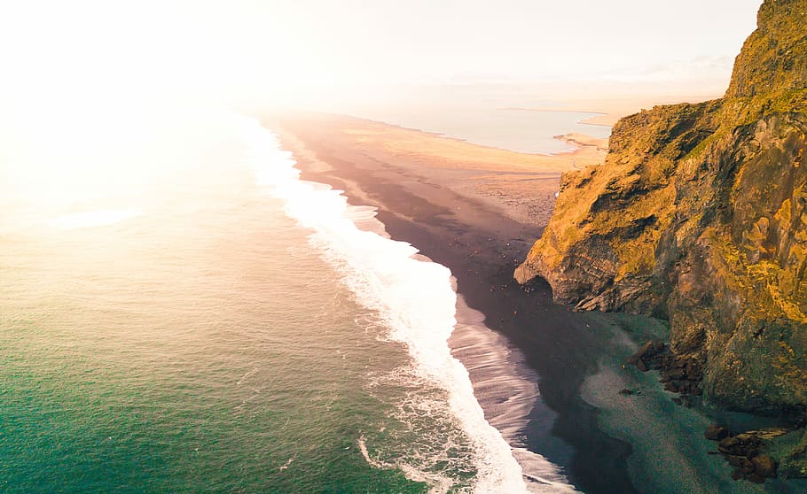 sea waves crashing on seashore, aerial photography of beach beside mountain during daytime HD wallpaper