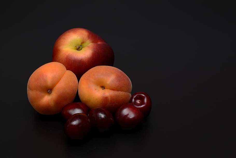 Apples and orange fruit with black background, apricots, nectarine