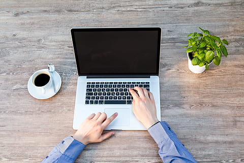 person wearing blue long-sleeved dress shirt near silver MacBook HD wallpaper