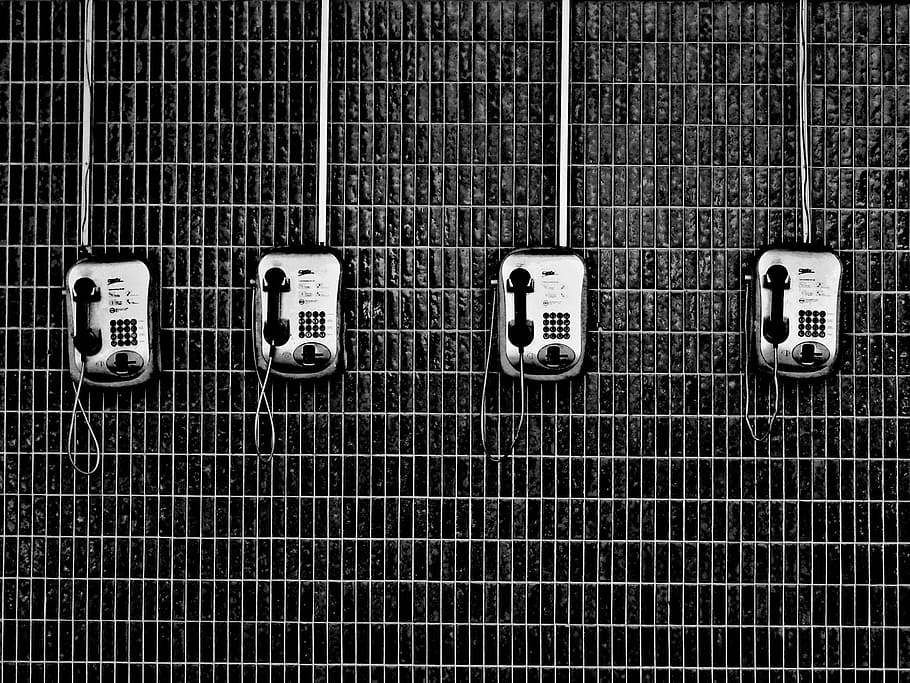 four black-and-grey telephones, four silver telephones on wall
