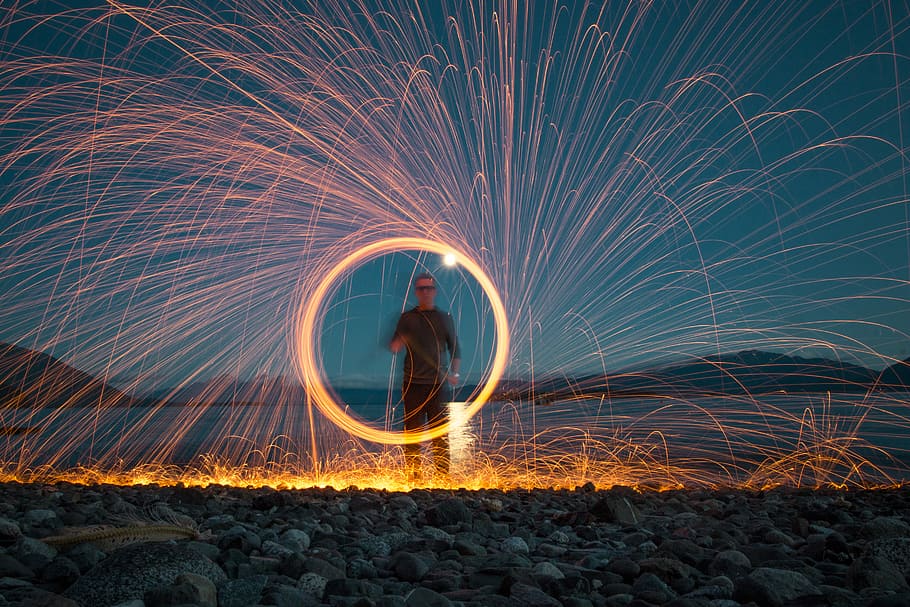 steel wool man holding firecrackers, steel-wool photography of man standing on plain field HD wallpaper