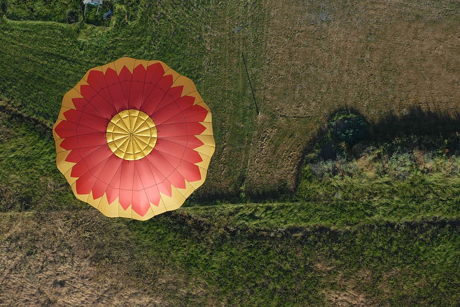 aerial photo of hot air balloon flying in the air, aerial photography of yellow and red hot air balloon above green grass field during daytime, HD wallpaper