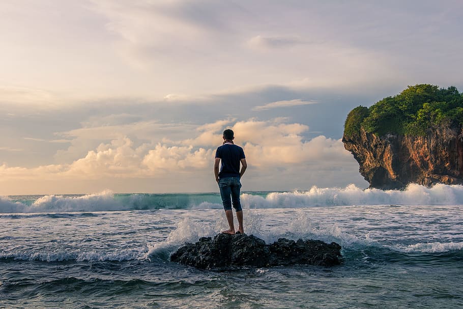 Man Standing on Stone Near Seashore during Sunrise Photography HD wallpaper