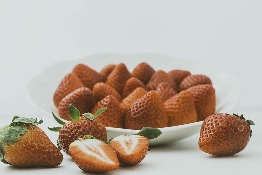 strawberries in round plate, brown strawberries on white ceramic bowl