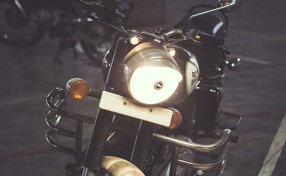 black standard motorcycle, turned on headlight of Royal Enfield motorcycle
