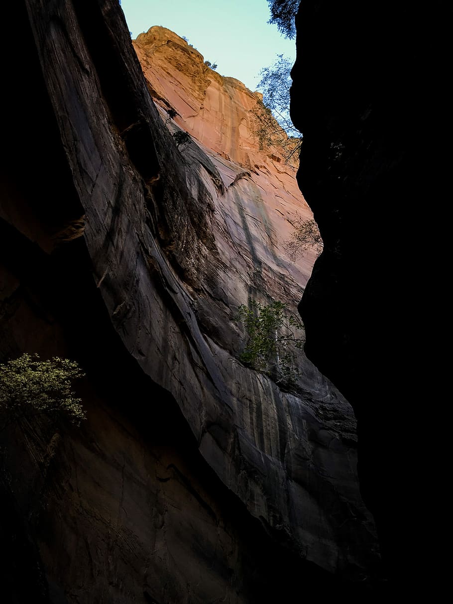 mountain face under blue sky during daytime, low-angle photography of cave during daytime HD wallpaper