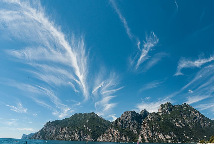 green tree-covered rocky mountain island under blue skies, rock formation under blue sky HD wallpaper