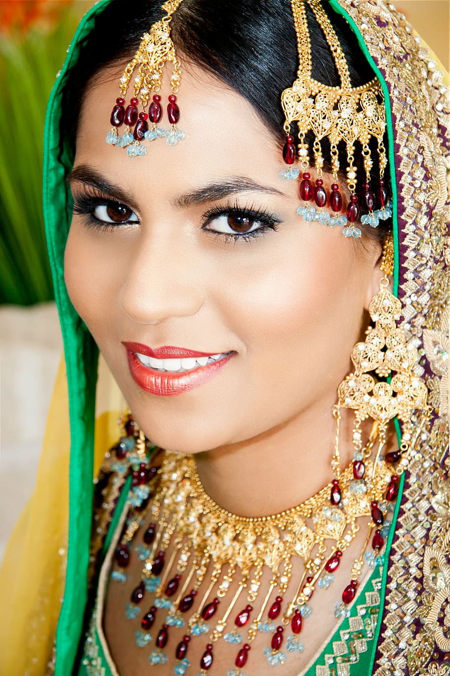 woman wearing gold-colored red and blue gemstone jewelries, woman smiling
