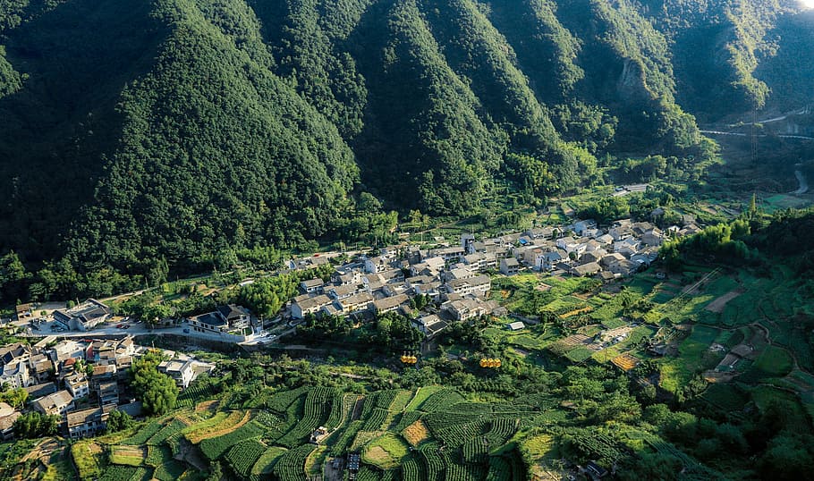 houses on valley surrounded by hills at daytime, aerial photography of rural area with mountains during daytime