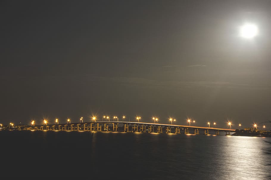 brown bridge with lights at dayttime, concrete bridge with lights between gray sky and water HD wallpaper
