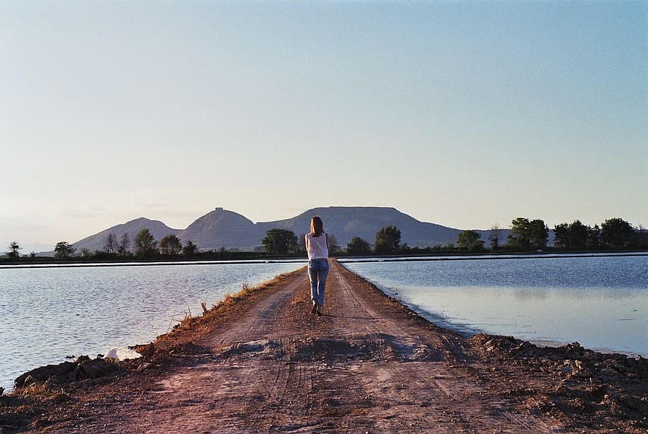 woman wearing blue jeans and white top near body of water at daytime HD wallpaper